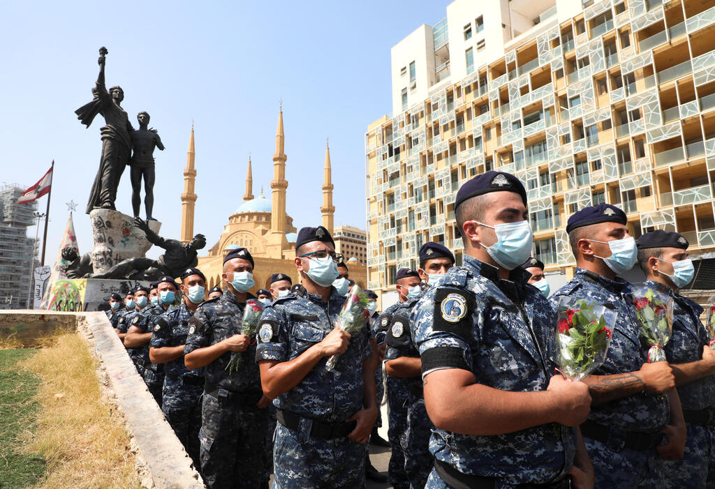 Members of internal security forces march and hold flowers as they mark one-year anniversary of Beirut port explosion 