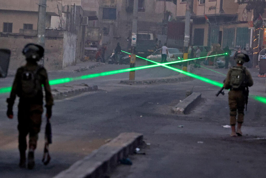 Palestinian protesters use laser torches during a demonstration against the Israeli settlers' outpost of Eviatar, in the town of Beita, near the West Bank city of Nablus, on August 8, 2021