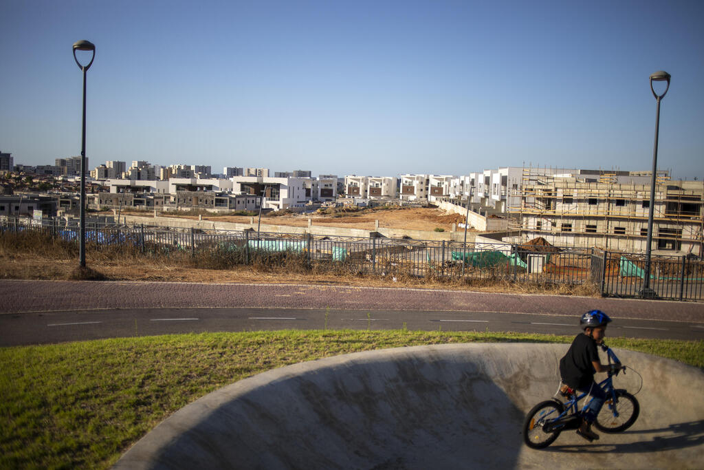 A boy rides his bicycles in a public park overlooking a construction site in Sderot, Israel, Wednesday, July 21, 2021