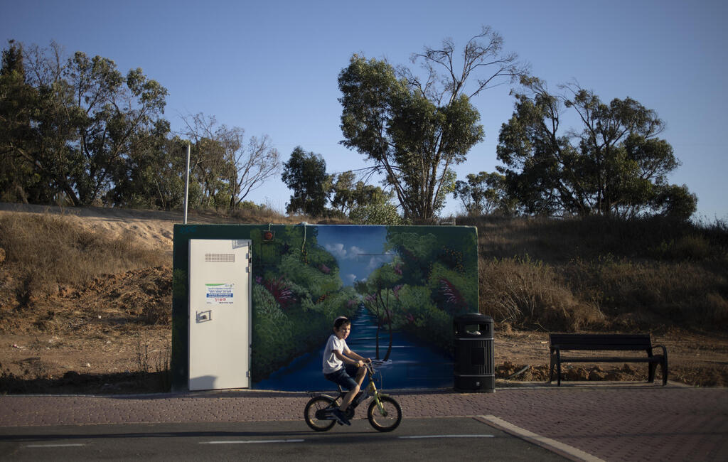 A boy rides his bicycles past a painted concrete bomb shelter placed in a public park in Sderot, Israel, July 21, 2021
