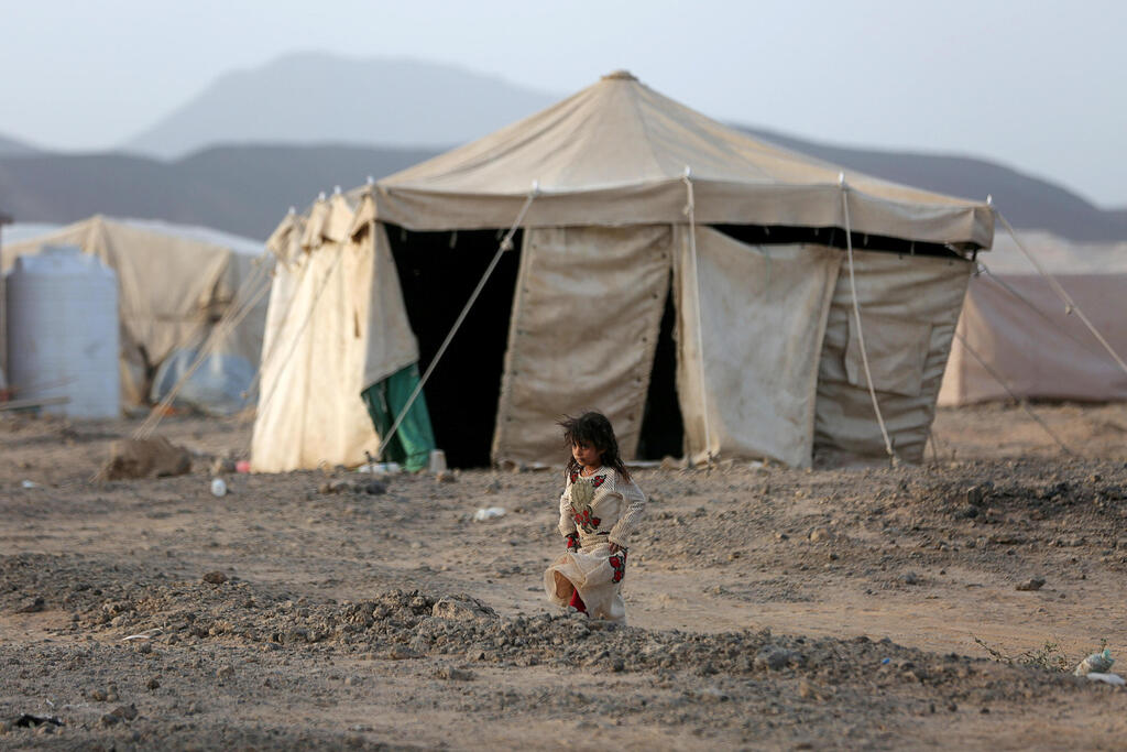 A girl walks by a tent in a camp for internally displaced people in Ma'rib province, Yemen in April 