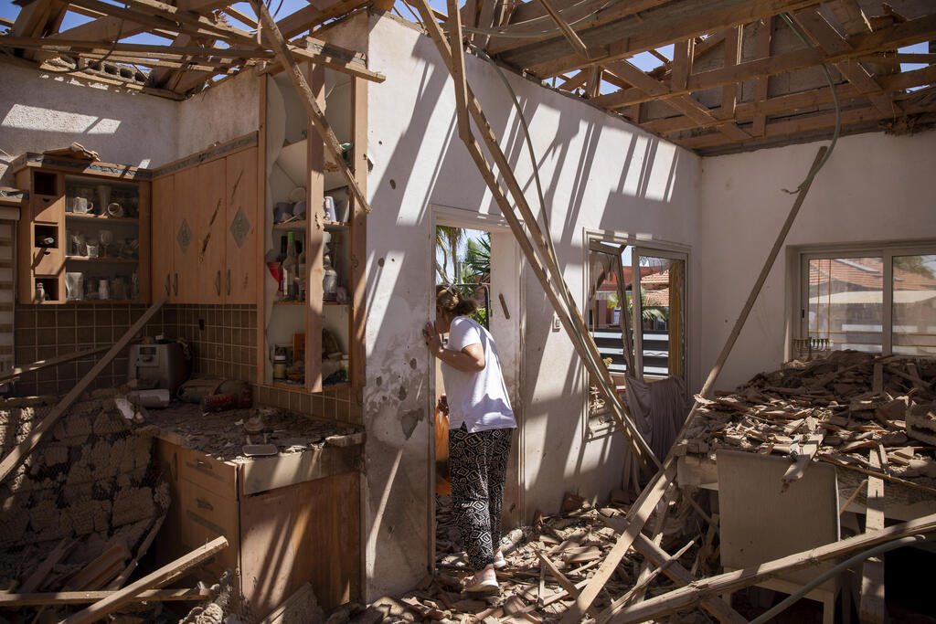 A woman surveys her damaged home after it was struck by a rocket fired from the Gaza Strip, in Sderot, May 15, 2021