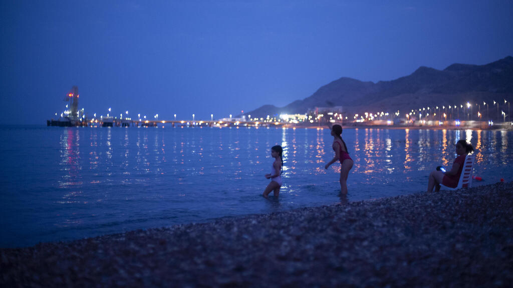 Kids play in the Red Sea beachfront backdropped by the Europe-Asia Pipeline Company (EAPC) oil jetty in Israel's southern city of Eilat, Thursday, Aug, 5. 2021 