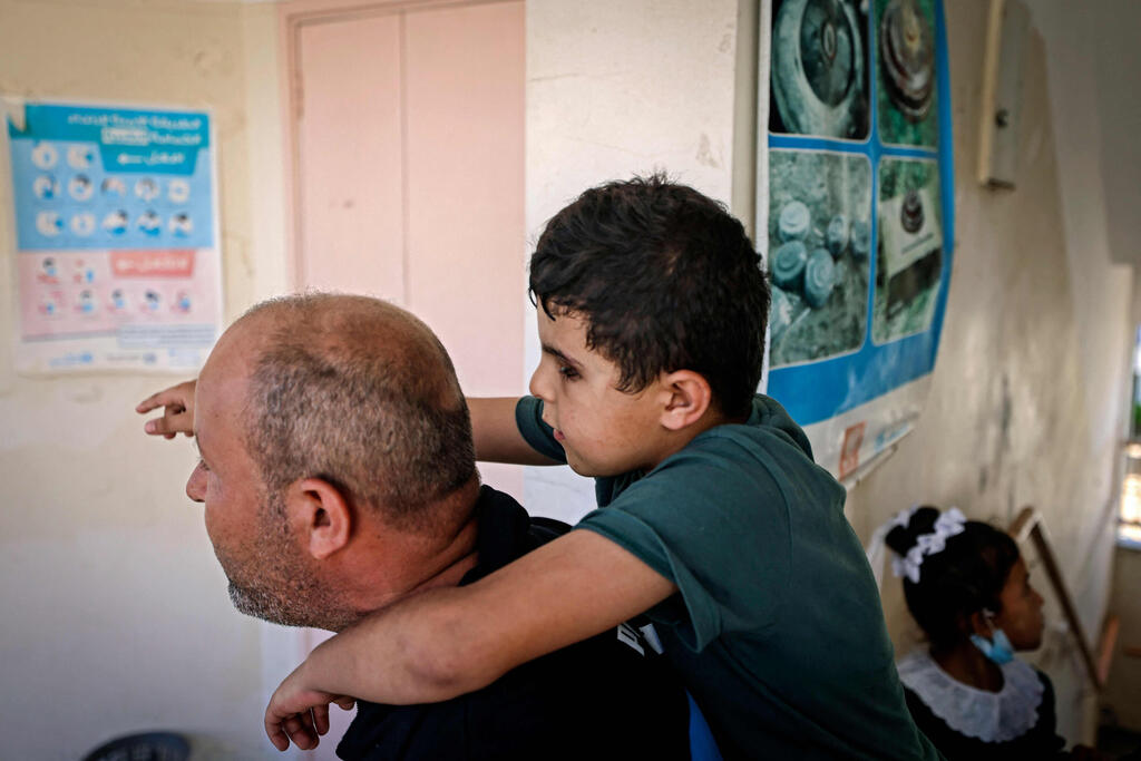 Palestinian pupil Mohammed Shaban's father Hani carries the young boy to class, at school in beit Lahia in the northern Gaza Strip, on August 17, 2021