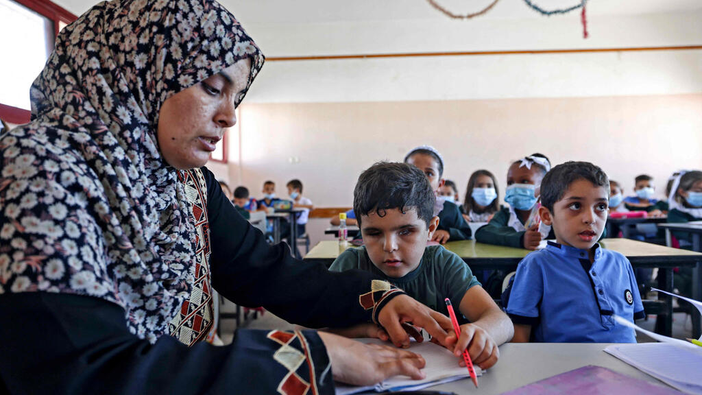 Palestinian pupil Mohammed Shaban is helped by his mother Somaya during class in beit Lahia, in the northern Gaza Strip