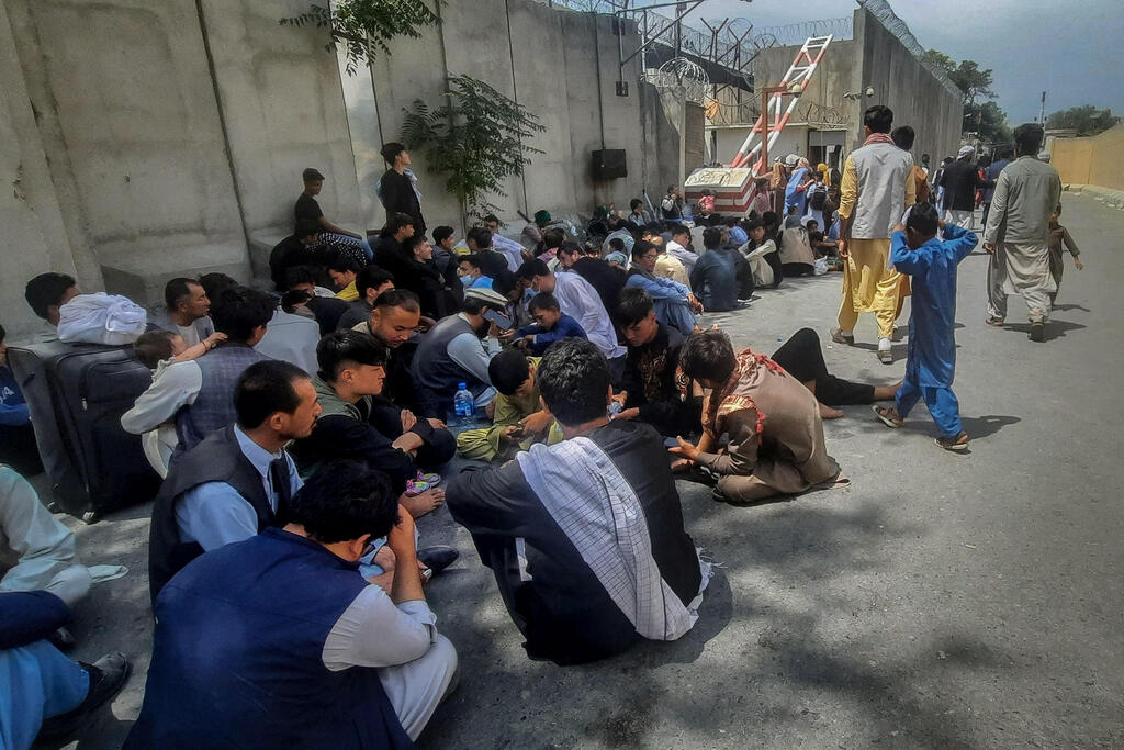 Afghan people sit outside the French embassy in Kabul on August 17, 2021 waiting to leave Afghanistan 