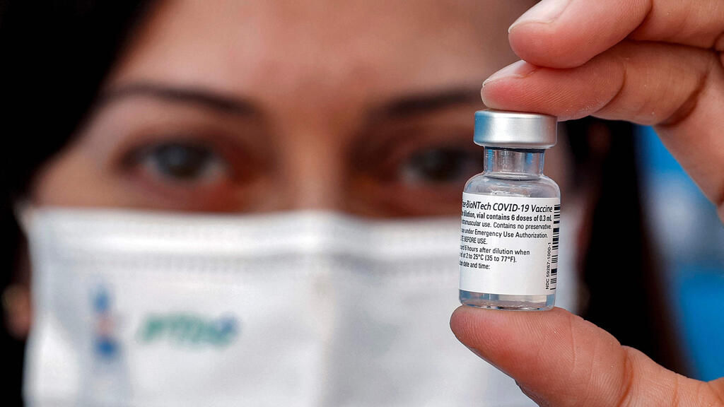 A medic holds up a vial of the Pfizer-BioNTech COVID-19 coronavirus vaccine at a vaccination centre at the Atid al-Najah High School for the Sciences at the city of Taibeh in northern Israel on August 19, 2021 