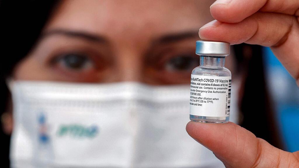 A medic holds up a vial of the Pfizer-BioNTech COVID-19 coronavirus vaccine at a vaccination centre at the Atid al-Najah High School for the Sciences at the city of Taibeh in northern Israel on August 19, 2021 