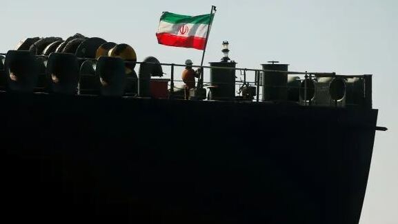 A crew member raises the Iranian flag on Iranian oil tanker Adrian Darya 1, previously named Grace 1, as it sits anchored after the Supreme Court of the British territory lifted its detention order, in the Strait of Gibraltar