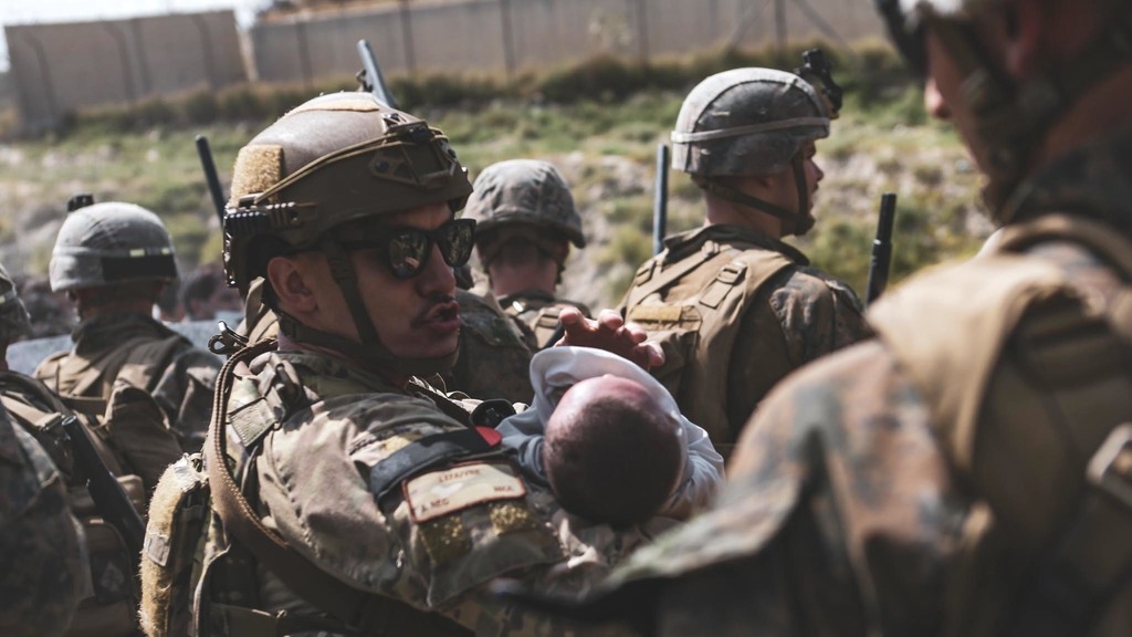  A U.S. serviceman at the Kabul airport holds an Afghan baby before his extraction from Afghanistan on Saturday 