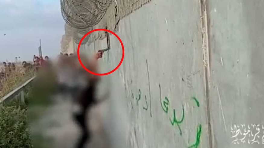 A Palestinian gunman fires through a hollow in the Gaza border wall, critically injuring an Israeli Border Police member on August 21 פלסטיני יורה לכיוון חיילים בהפגנה על גדר גבול עזה