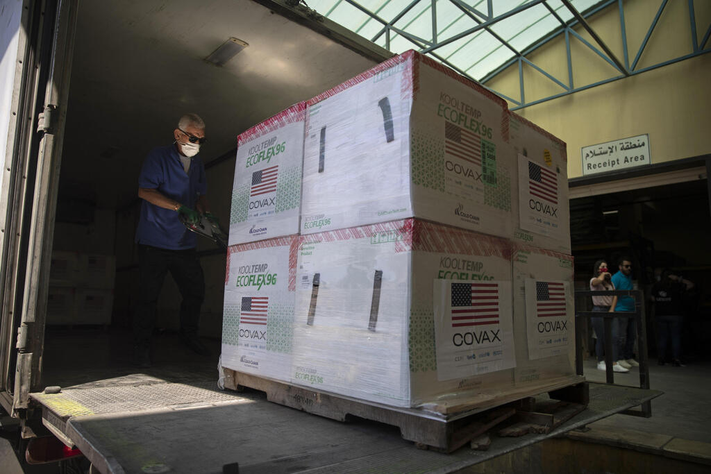 Palestinians unload a shipment of the Moderna coronavirus vaccine donated by the U.S, at the Palestinian health ministry, in the West Bank village of Salem, near Nablus 