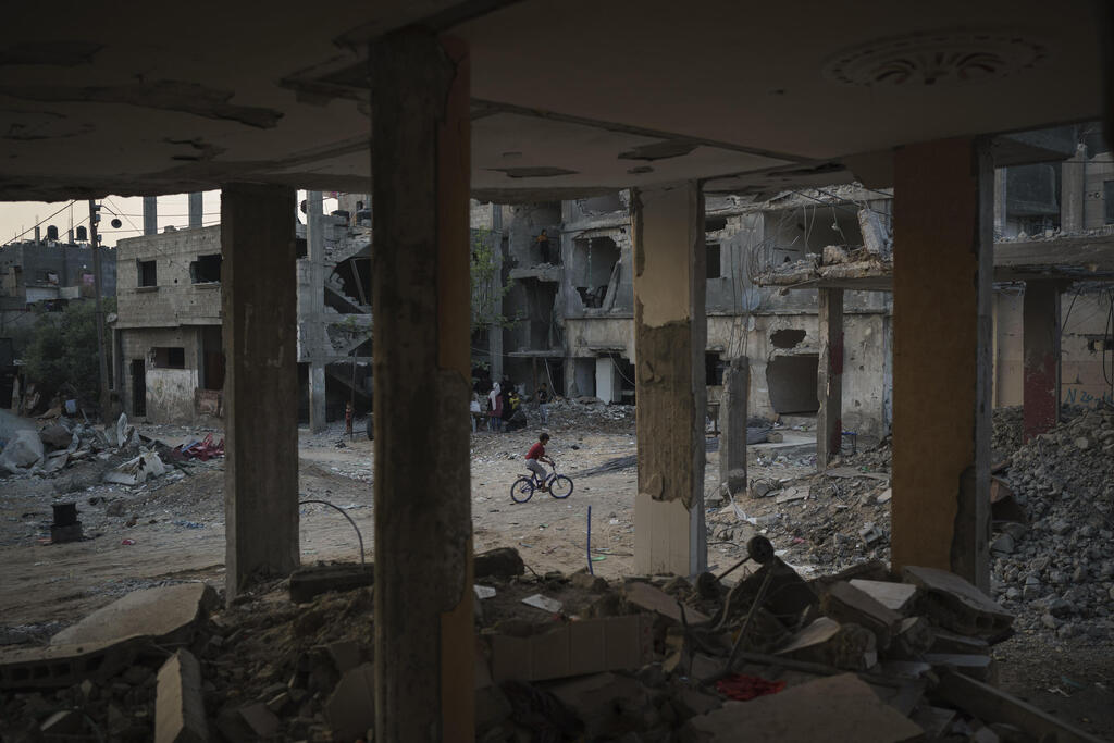 A boy rides his bike along Al-Baali Street, next to houses heavily damaged by airstrikes during the recent 11-day war in Beit Hanoun, northern Gaza Strip, Sunday, June 13, 2021