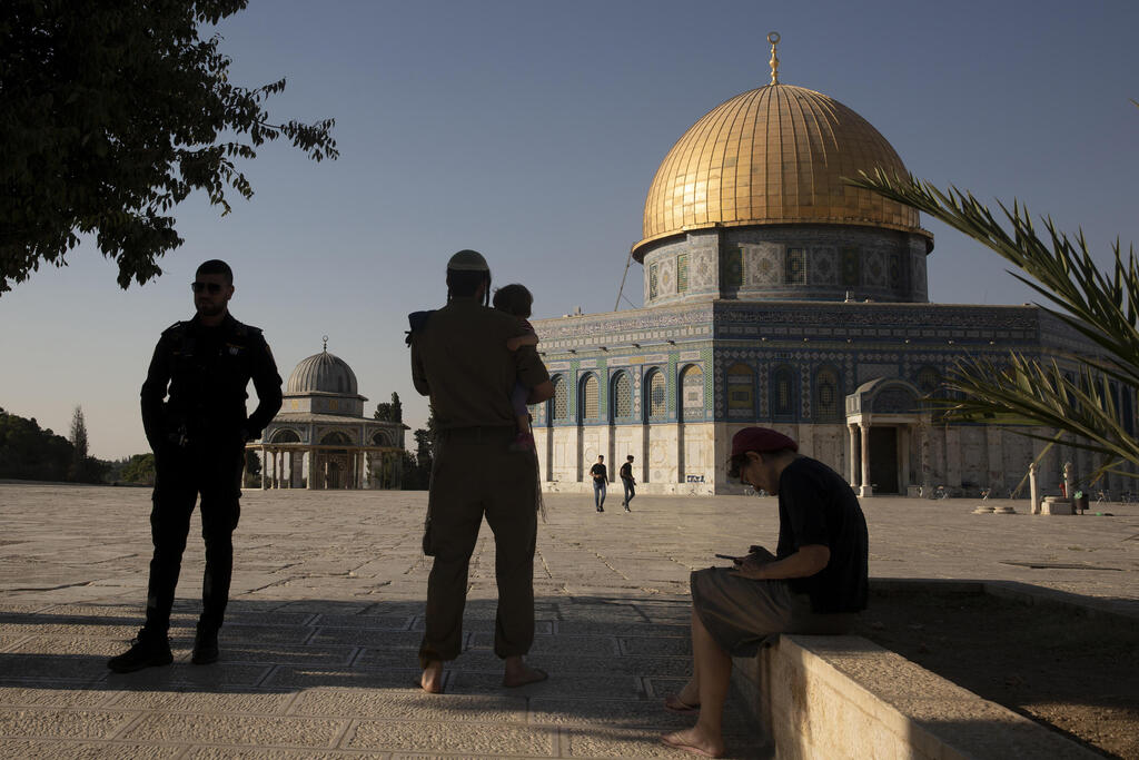 An Israeli police officer stands guard as a religious Jew in army uniform visits the Temple Mount in the Old City of Jerusalem, Tuesday, Aug. 3, 2021