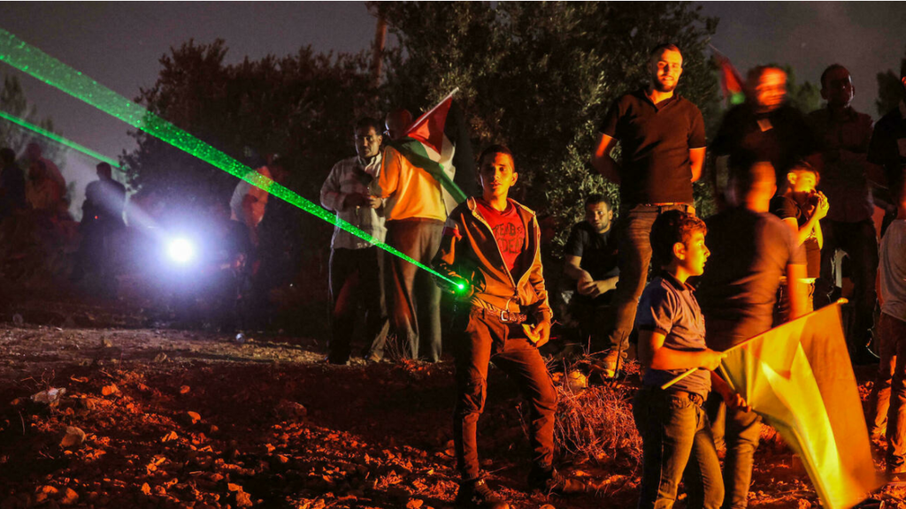 Palestinian protesters in Beita use laser pointers during a demonstration against the Israeli settler outpost of Eviatar on July 1, 2021
