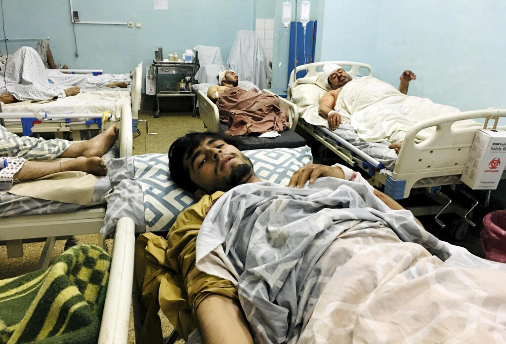 Wounded Afghans lie on a bed at a hospital after a deadly explosions outside the airport in Kabul