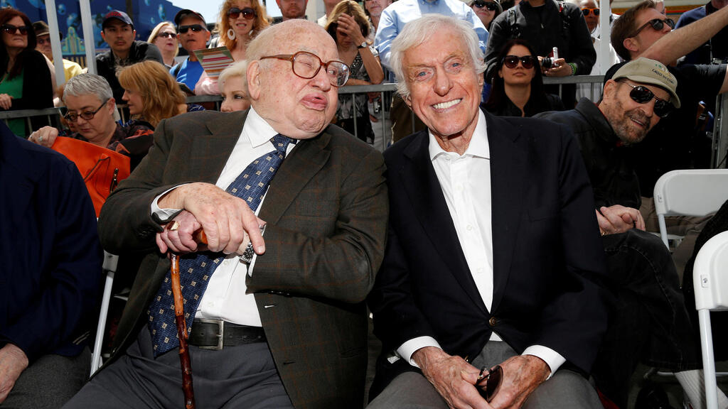 Actor Dick Van Dyke smiles as Ed Asner sticks his tongue out to make a face for the camera 