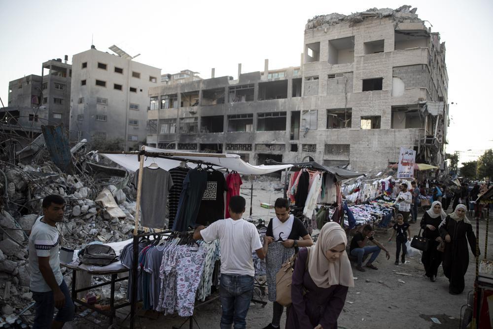 Palestinian street vendors display clothes for sale next to the rubble of destroyed buildings were hit by Israeli airstrikes during an 11-day war between Gaza's Hamas rulers and Israel 
