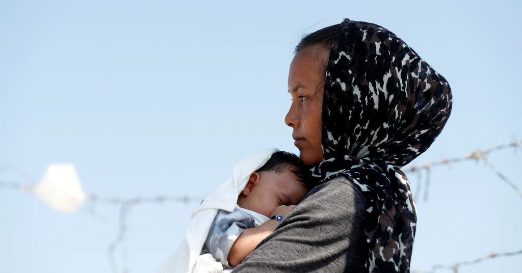An Afghan woman and her month-old son are seen outside the new temporary camp for migrants and refugees, on the island of Lesbos, Greece 