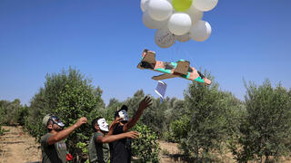פלסטינים מפריחים בלונים עם תמונות הרוגים מהעימותים ומסרי איום
