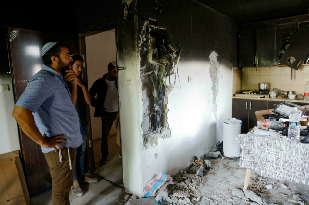Israelis stand in a home that was damaged by fire during the intra-communal violence in Lod