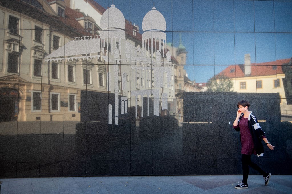 A woman passes a wall with an image of the former Neolog Synagogue next to the Holocaust Memorial located in the center of Bratislava's Old Town