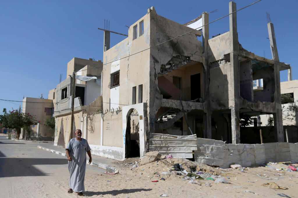 A Palestinian man walks outside a house that was damaged by Israeli strikes during Israel-Hamas fighting last May, in Khan Younis in southern Gaza Strip 
