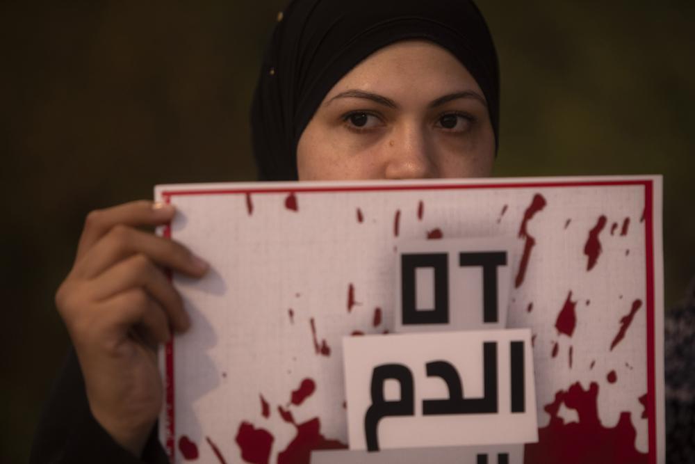 Protesters hold signs and chant slogans during a demonstration against violence near the house of Public Security Minister Omer Barlev in the central Israeli town of Kokhav Ya'ir 