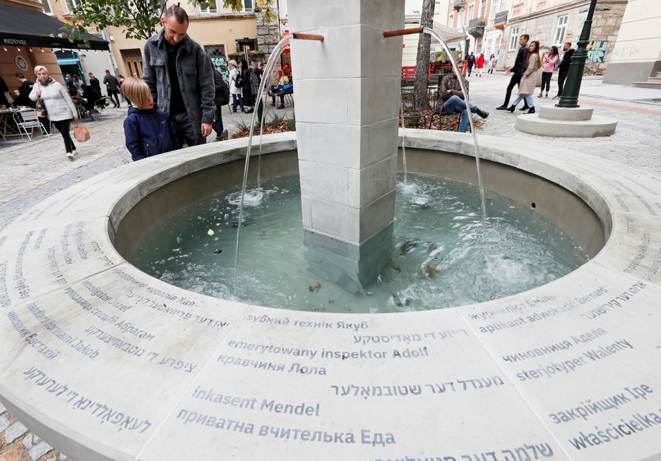 People stand by the fountain, which is engraved with the names of 70 Jews who lived in the area before World War Two, in Lviv, Ukraine
