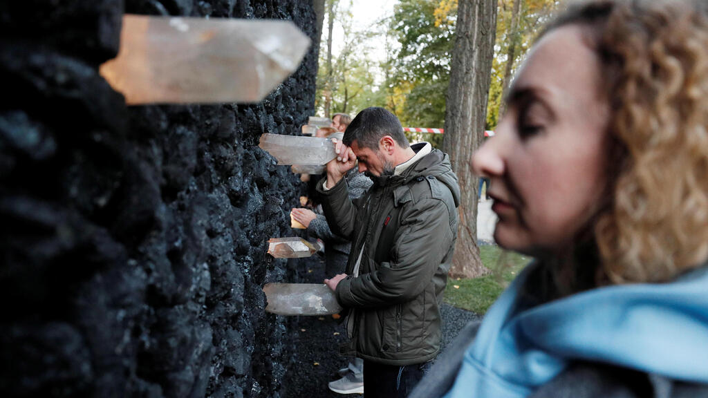 People take part in a performance by artist Marina Abramovic next to her artwork "Crystal Wall of Crying" at Babyn Yar, the site of one of the biggest massacres of the Holocaust during World War Two, in Kyiv, Ukraine 
