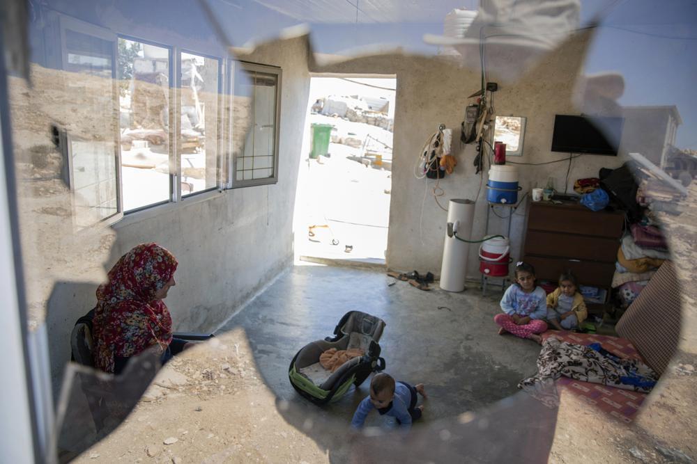 A Palestinian family is seen through their house's shattered window following a settlers' attack from nearby settlement outposts on the Bedouin community, in the West Bank village of al-Mufagara, 