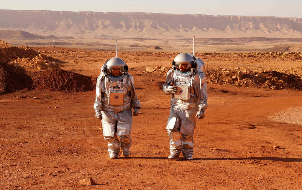 Astronauts from a team from Europe and Israel walk in spacesuits during a training mission for planet Mars at a site that simulates an off-site station at the Ramon Crater in Mitzpe Ramon in the southern Negev desert on October 10, 2021