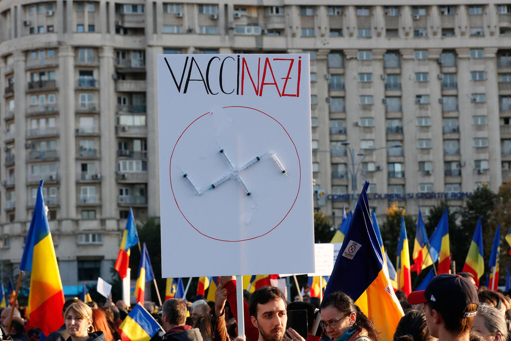 Man holding banner with syringes in the shape of a Swastika during a rally against Romanian government's new health measures amid country's fourth wave of COVID-19, in front of government headquarters in Bucharest, Romania, October 2, 2021