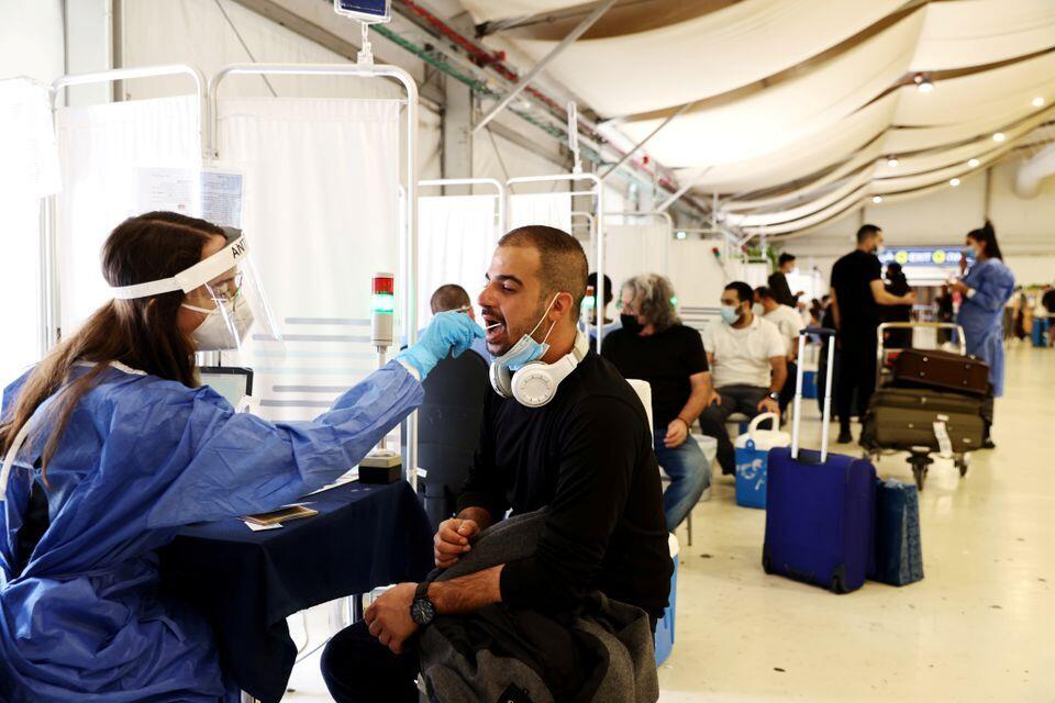 A healthcare worker takes a swab sample from a traveller for a coronavirus disease (COVID-19) test at the Ben Gurion International Airport 