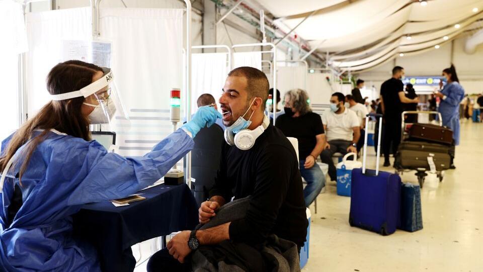 A healthcare worker takes a swab sample from a traveller for a coronavirus disease (COVID-19) test at the Ben Gurion International Airport 