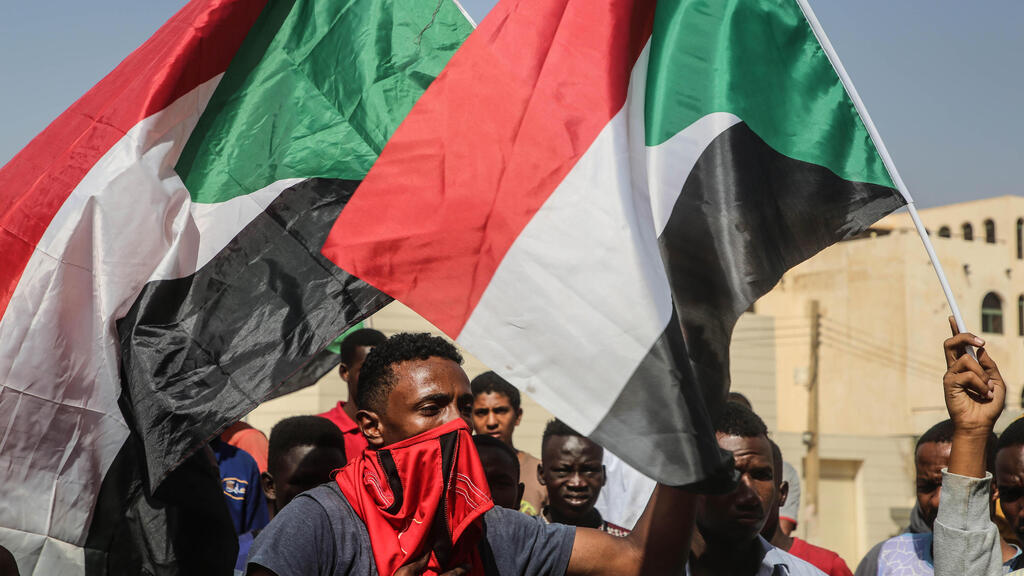 A protester waves a flag during what the information ministry calls a military coup in Khartoum, Sudan