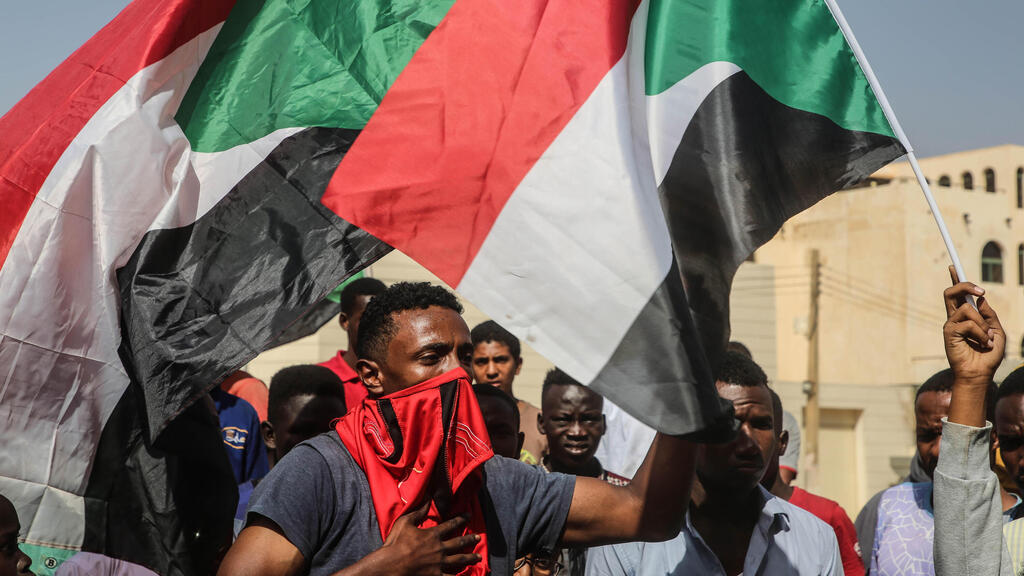 A protester waves a flag during what the information ministry calls a military coup in Khartoum, Sudan