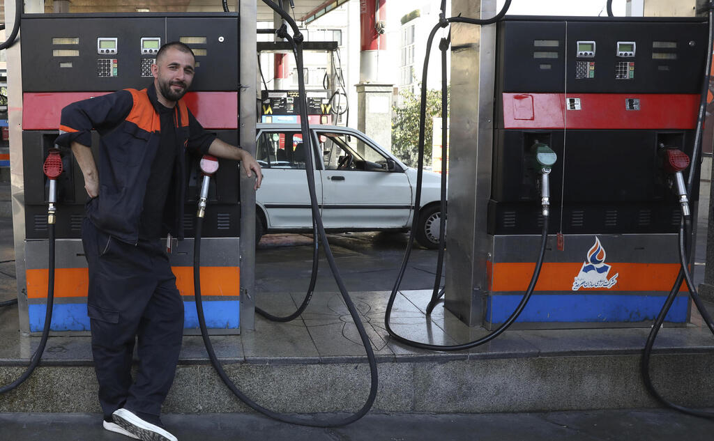 A worker leans against a gasoline pump that has been turned off, at a gas station in Tehran, Iran, Tuesday, Oct. 26, 2021