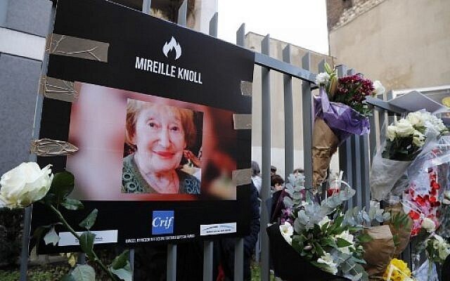 A photograph of murdered Holocaust survivor Mireille Knoll is placed along with flowers on the fence surrounding her building in Paris on March 28, 2018 
