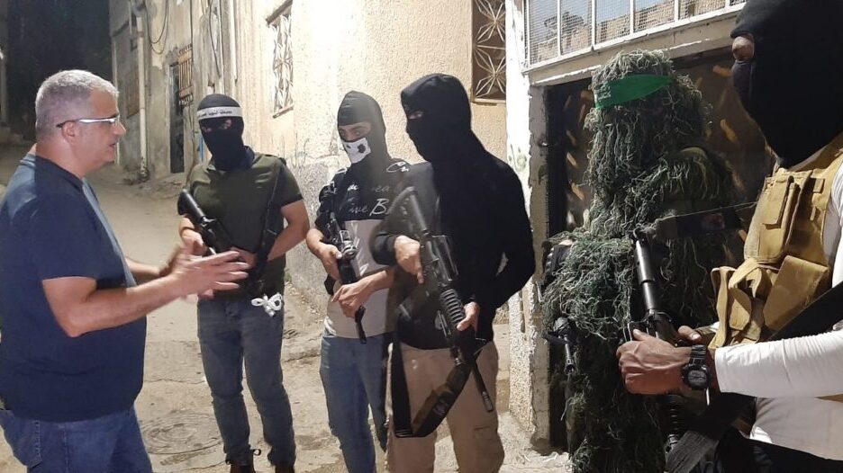 Masked gunmen from different Palestinian factions speak to The Media Line reporter Mohammad Al-Kassim while on patrol at the camp on October 26, 2021 
