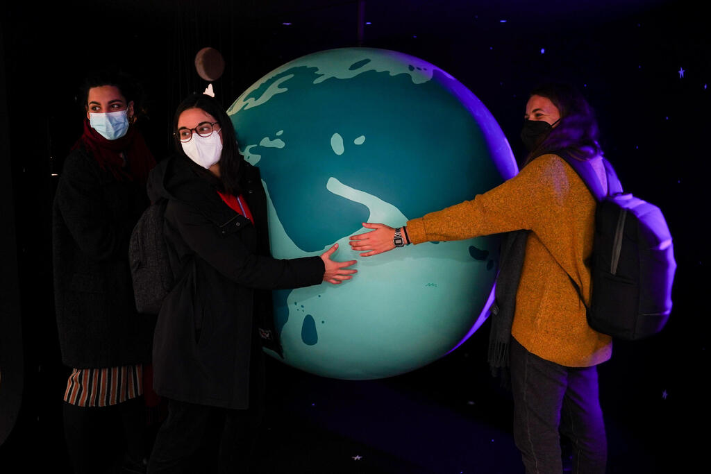 A group of delegates wrap their hands around a display of the world on October 31, 2021 in Glasgow, Scotland