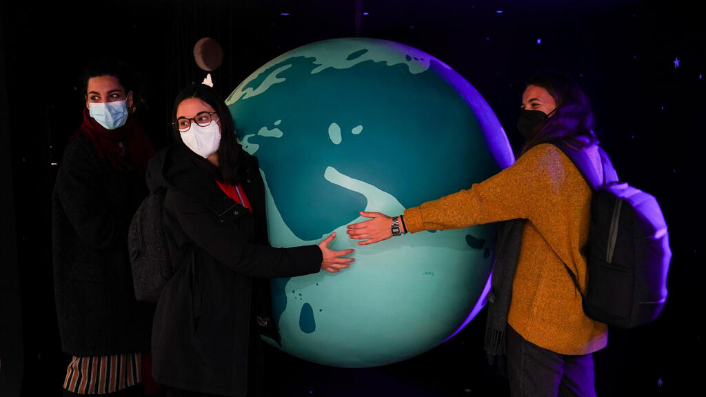 A group of delegates wrap their hands around a display of the world on October 31, 2021 in Glasgow, Scotland