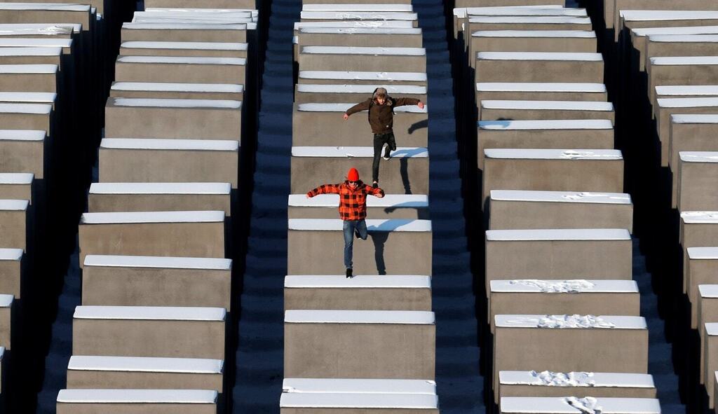 People jump from concrete elements of the Holocaust memorial in Berlin 