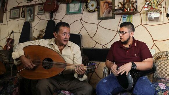 Palestinian musician Khader El-Bayed, who turned his house into a music hub, trains a man how to use music instruments in Gaza City,