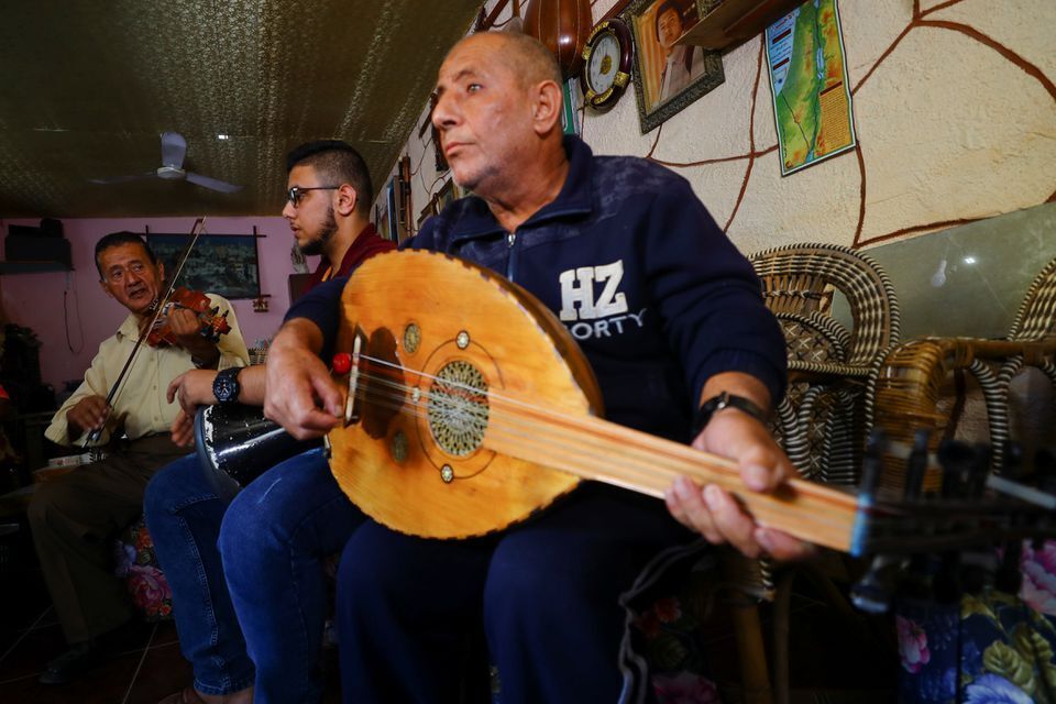 Palestinian musician Khader El-Bayed, who turned his house into a music hub, trains men how to use music instruments in Gaza
