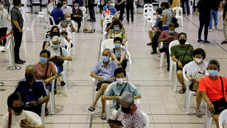 אנשים נחים לאחר קבלת החיסון במרכז חיסונים בסינגפור