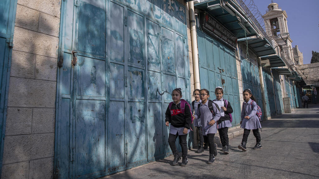 Palestinian children walk past closed souvenir shops in Bethlehem last week 