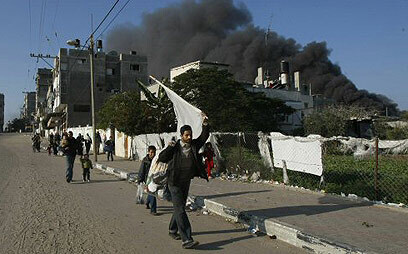 Gazans walking as smoke bellows from an IAF strike during the 2009 Gaza War