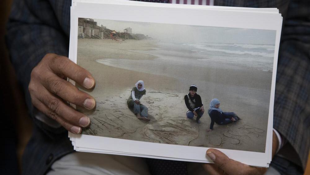 Dr. Izzeldin Abuelaish holds a photograph of his daughters and niece on the beach in Gaza