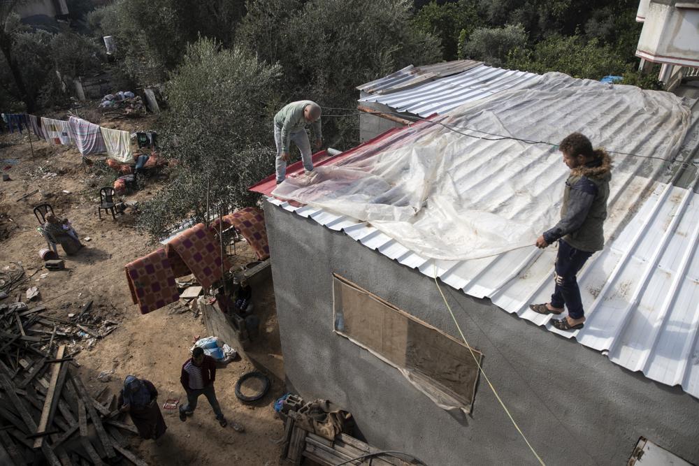 Palestinians cover the roof of their house with nylon to protect it from rain leaks after it was damaged during the 11-day Gaza war in May 2021, in the town of Beit Lahiya, northern Gaza Strip 